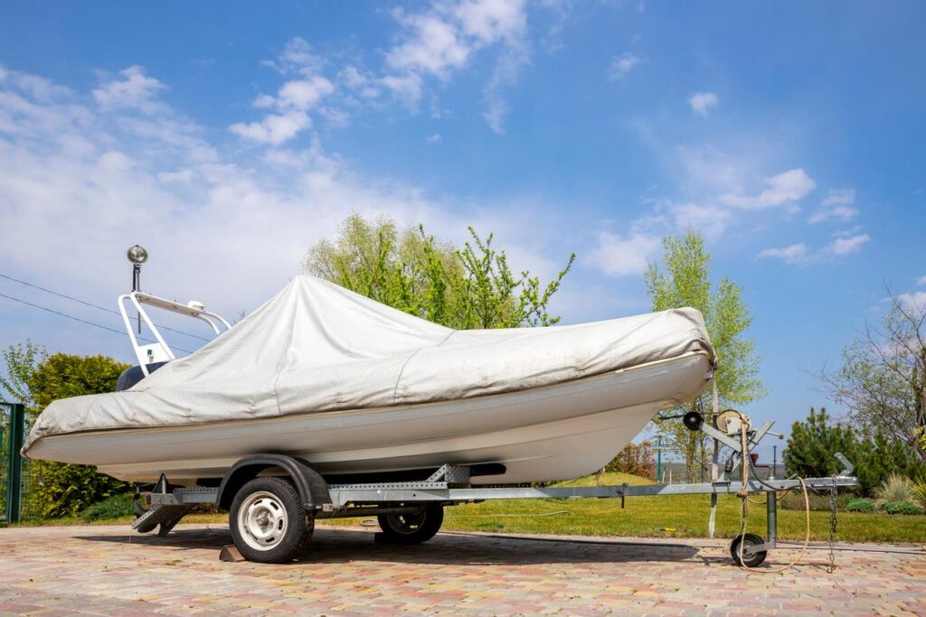 Large boat covered with a tarp parked at a storage facillity.